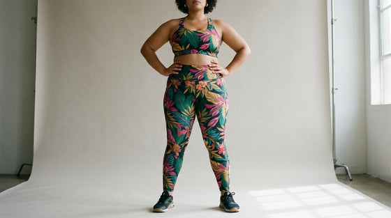 Plus-size woman standing with hands on hips wearing bold tropical floral patterned activewear leggings