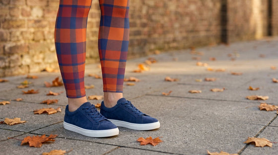 Legs from the knee down in FIERCEPULSE Fall Plaid Leggings with navy suede sneakers that match the navy in the plaid, on an autumn sidewalk