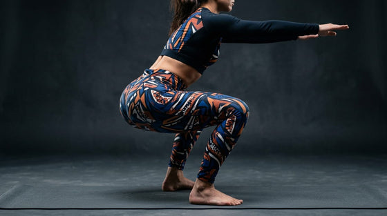 Athletic woman in deep squat position wearing bold geometric-patterned leggings showing fabric opacity at full flexion